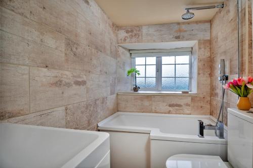 La salle de bains est pourvue d'une baignoire, de toilettes et d'une fenêtre. dans l'établissement Finest Retreats - Cloggers Cottage, à Darley