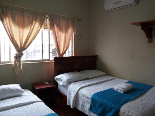 a bedroom with two beds and a window at Hostal Miconia in Puerto Ayora