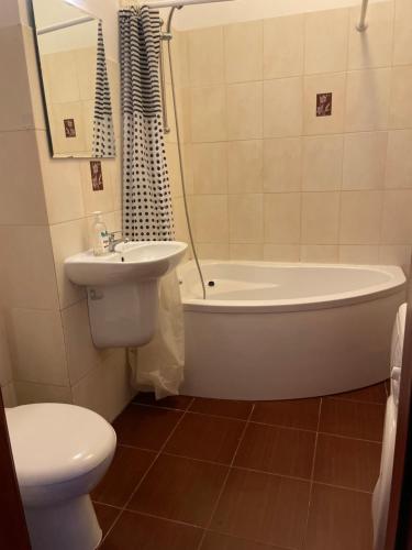 a bathroom with a toilet and a tub and a sink at Pokoje Mokotów in Warsaw