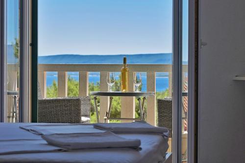 a table with a bottle and wine glasses on a balcony at Guest House Marija in Bol