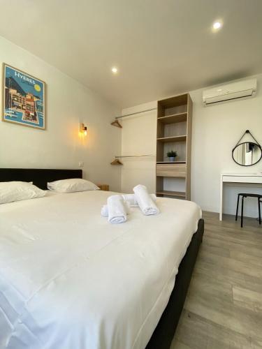 une chambre avec un grand lit blanc avec des serviettes dessus dans l'établissement La Clé -Climatisation - Parking privé - Idéale - Professionnels - Familles - Amis, à Hyères