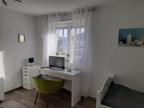 een kamer met een bureau met een computer en een groene stoel bij Ferienwohnung Weinand in Birresborn