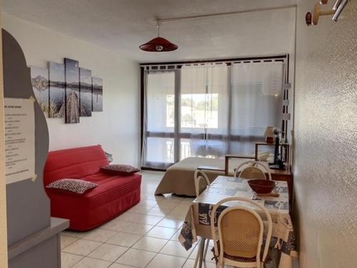 un salon avec un canapé rouge et une table dans l'établissement Appartement cosy avec balcon, proche des Thermes, animaux admis, climatisation et Wifi inclus - FR-1-503-128, à Balaruc-les-Bains