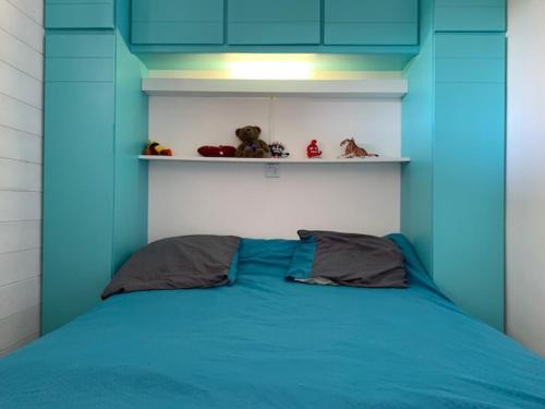 - un lit bleu avec deux oreillers dans une chambre dans l'établissement Appartement 2 étoiles à 5 min des thermes avec parking et clim, animaux acceptés - FR-1-503-129, à Balaruc-les-Bains