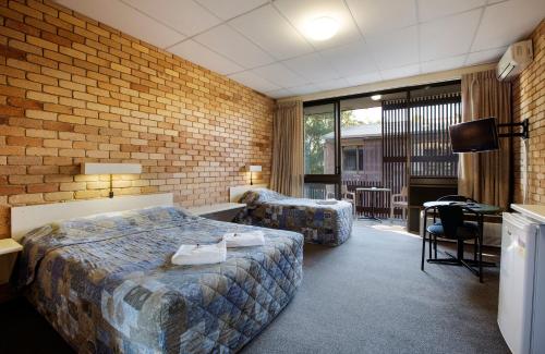 Pokój hotelowy z łóżkiem, biurkiem i telewizorem w obiekcie Villa Noosa Hotel w mieście Noosaville