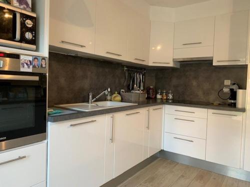 une cuisine avec des armoires blanches et un évier dans l'établissement Villa 95m² avec jardin, climatisation et Wifi à Balaruc-les-Bains - ⭐⭐⭐ Etoiles - FR-1-503-126, à Balaruc-les-Bains