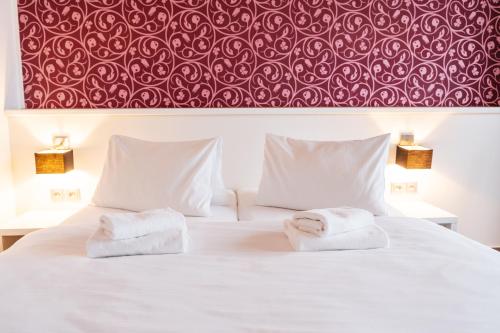 a bedroom with two towels on a bed with a red wall at K-Triumf Resort in Velichovky