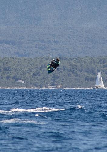 a person in the air over the water with a sailboat at Guest House Marija in Bol