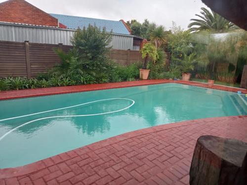 a swimming pool in a yard with a red brickickedickedickedickedickedicked at Ay Jay's Guesthouse in Bloemfontein