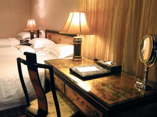 a bedroom with a desk with a lamp and a bed at Royal Seasons Hotel Taipei ‧ Nanjing W. in Taipei