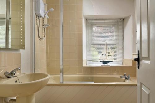 a bathroom with a sink and a tub and a window at Finest Retreats - The Cottage at Greystoke in Greystoke