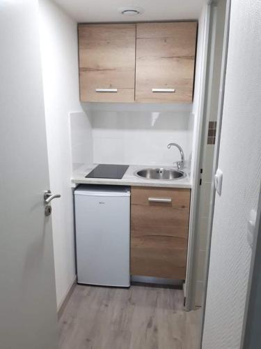 una pequeña cocina con fregadero y nevera blanca en Studio refait à neuf., en Mers-les-Bains