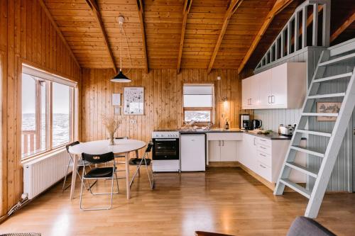 cocina con mesa, sillas y escalera en Hlíd Cottages en Myvatn