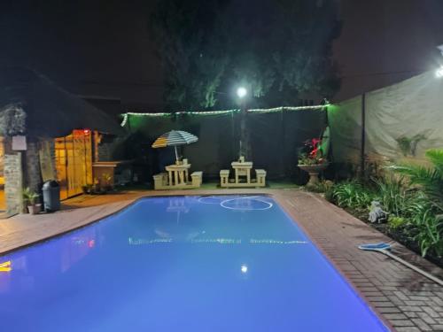 an empty swimming pool at night with an umbrella at Ay Jay's Guesthouse in Bloemfontein