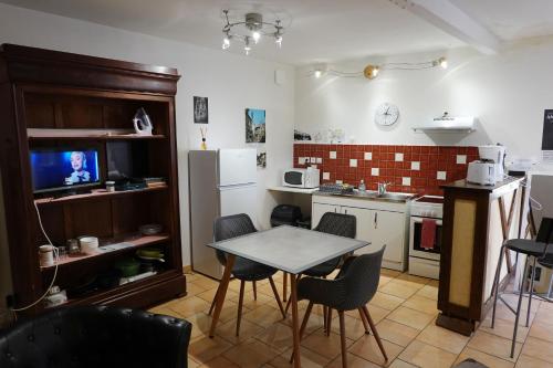 a kitchen with a table and chairs and a television at Appart' de la collégiale in Bourbon-Lancy