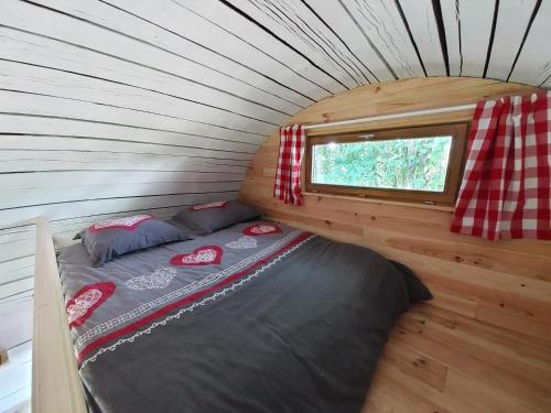 uma cama numa pequena casa com uma janela em L'authentique Tonneau à Cidre d'Emma em Litteau