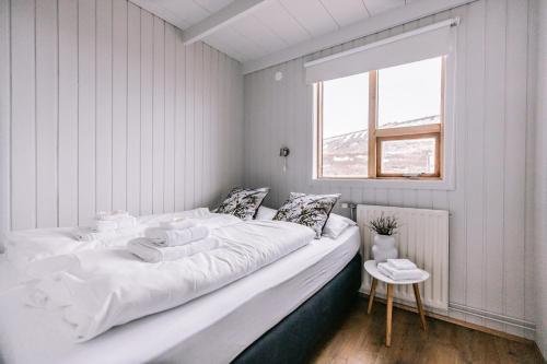 Cama blanca en habitación con ventana en Hlíd Cottages en Myvatn