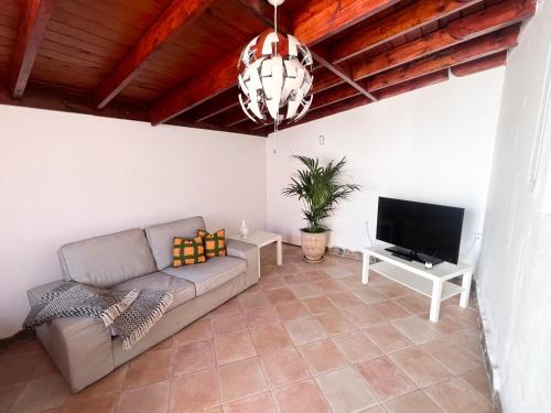 sala de estar con sofá y TV de pantalla plana en El Alegato Casa de Invitados en Antigua