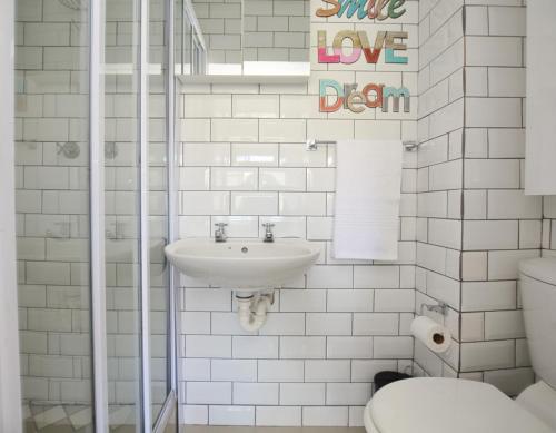Baño blanco con lavabo y aseo en Say Shells en Ciudad del Cabo