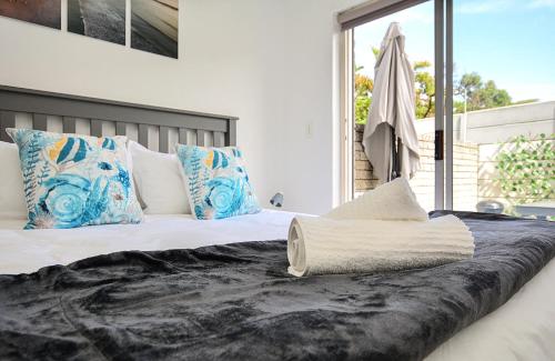 a bed with blue and white pillows and a window at Say Shells in Cape Town