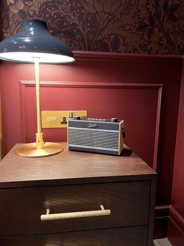 a lamp and a radio sitting on top of a dresser at Sun Street Hotel Shoreditch in London