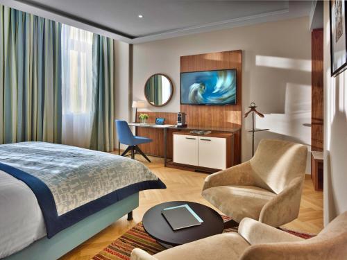 - une chambre avec un lit, une chaise et un bureau dans l'établissement EST Grand Hotel Savoy, à Budapest