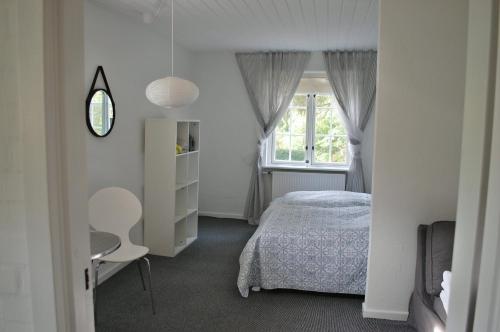 1 dormitorio con 1 cama, 1 silla y 1 ventana en Fredensborg Guesthouse en Fredensborg