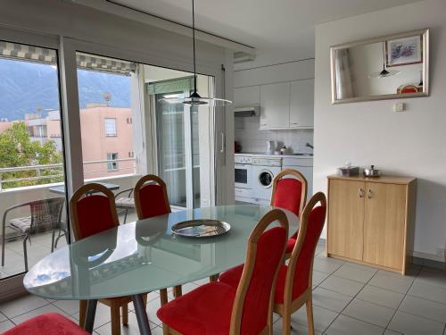 comedor con mesa de cristal y sillas rojas en Ascona: San Materno-Mary, en Ascona