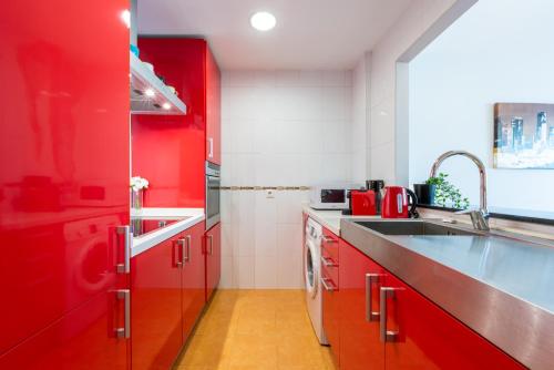 a red kitchen with a sink and red cabinets at Ferrandiz in Málaga