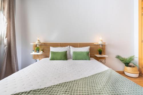 a bedroom with a large white bed with two green pillows at Ferrandiz in Málaga