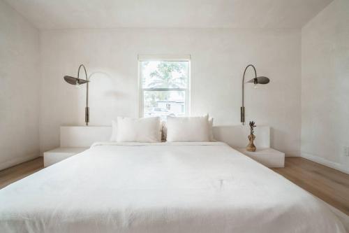 a white bedroom with a large white bed with two lights at Casa Terra Lumi in Fort Lauderdale