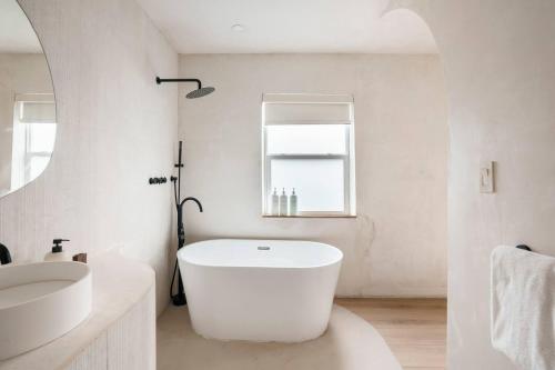 a white bathroom with a tub and a sink at Casa Terra Lumi in Fort Lauderdale