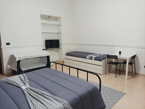 um quarto com duas camas, uma escrivaninha e uma TV em B&B Nancy em Nápoles