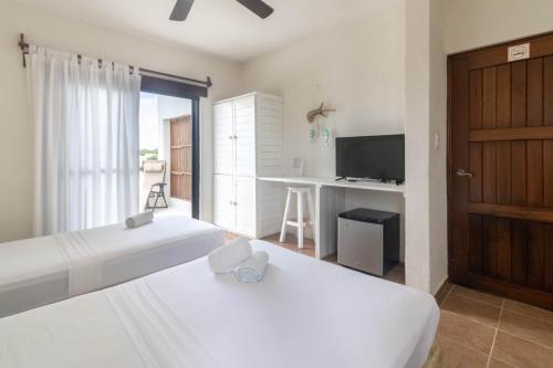 sypialnia z 2 łóżkami, biurkiem i telewizorem w obiekcie Hotel Boutique Pachamama w mieście Mahahual