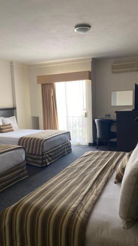 a hotel room with two beds and a desk at Hotel Zafra in Torreón