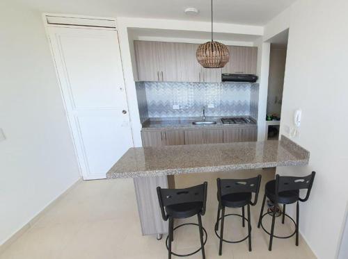 a kitchen with a counter and four stools at APARTAMENTO GIRARDOT BUENA UBICACIÓN in Girardot