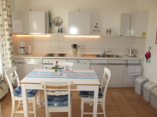a kitchen with a table with chairs and a sink at FeWo ABDENA DORN200 in Dornum