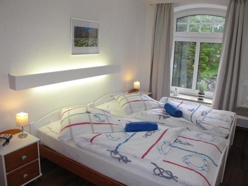 a bedroom with a white bed with red and blue pillows at FeWo ABDENA DORN200 in Dornum