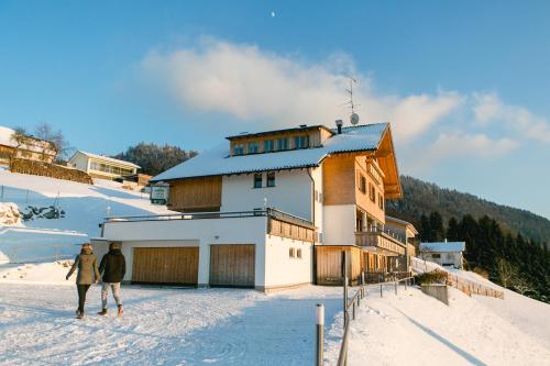 two people walking in the snow in front of a building at Hotel Dreiländerblick Dornbirn in Dornbirn