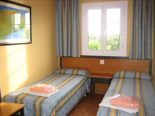 a hotel room with two beds and a window at Precioso apartamento de dos hab. en Calan Bosch in Ciutadella