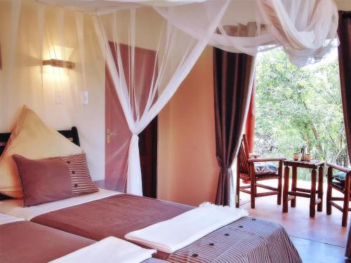 a bedroom with a bed with curtains and a window at Game Lodge bordering Kruger with splash pool in Phalaborwa