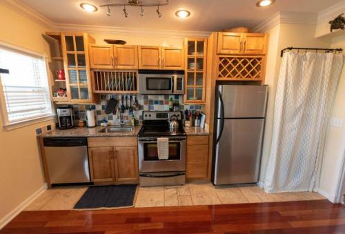 a kitchen with stainless steel appliances and wooden cabinets at Wine-Dine-Sunshine Cozy Flat in The Heart of DTSP in St Petersburg