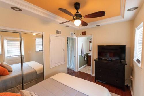 a bedroom with a ceiling fan and a television at Wine-Dine-Sunshine Cozy Flat in The Heart of DTSP in St Petersburg