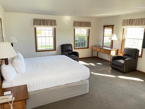een slaapkamer met een bed en 2 stoelen en een bureau bij Farmstead Inn and Conference Center in Shipshewana