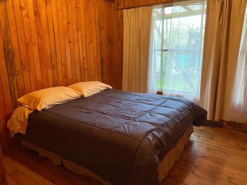 a bed in a wooden room with a window at Cabaña en Quinchamalí in Quinchamali