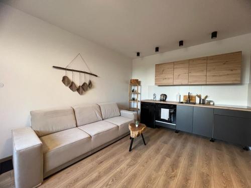 a living room with a white couch and a kitchen at Niron Apartamenty Królowej Jadwigi Złotów in Złotów