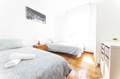 a white bedroom with two beds and a dresser at Apartamento cerra playa in Gijón