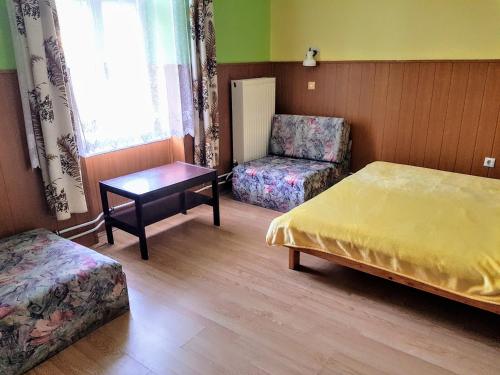 a bedroom with a bed and a chair and a table at Muskátli Üdülőház in Parádfürdő-Peres