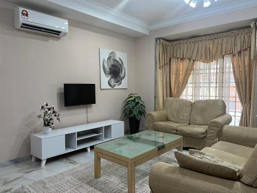 a living room with a couch and a tv at D’Lestari Homestay in Seri Kembangan