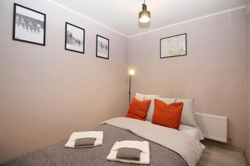 a bedroom with a bed with two orange pillows at Apartament Dzikowiec in Boguszów-Gorce